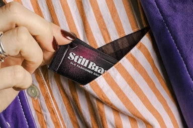 Hand holding a Still Branch packet in a striped fabric pocket